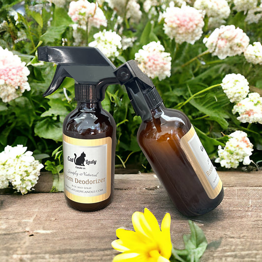 Two brown glass spray bottles with white labels, each with a black spray nozzle and displayed on a wooden surface with white flowers in the background.