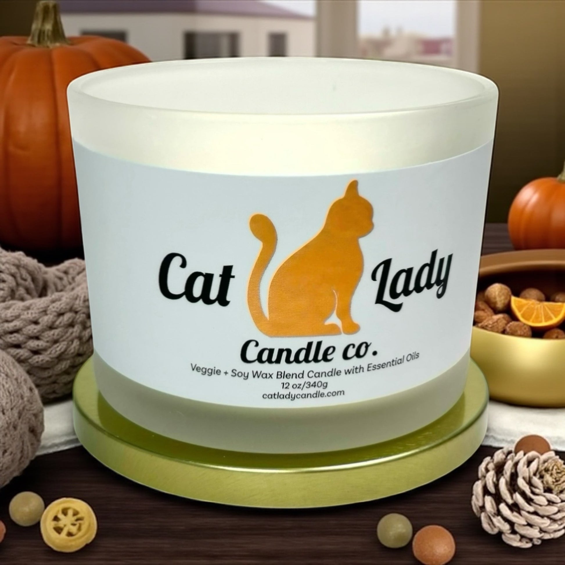 Candle with 'Cat Lady Candle Co.' label on a wooden surface with pumpkins and decorative items.