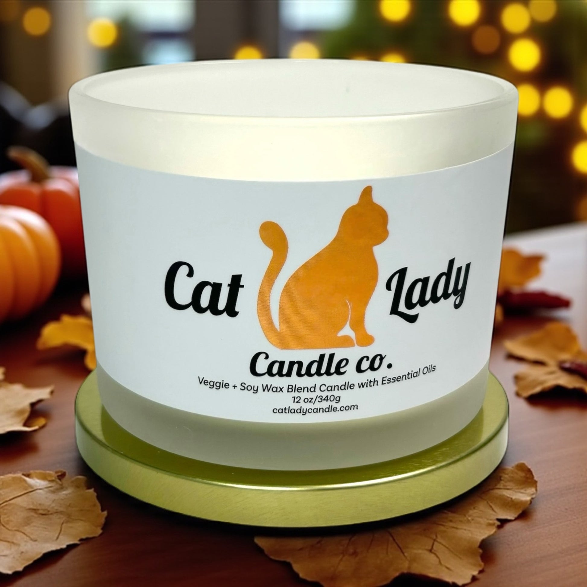 Candle with 'Cat Lady Candle Co.' label on a table with pumpkins and leaves in a fall themed cafe.